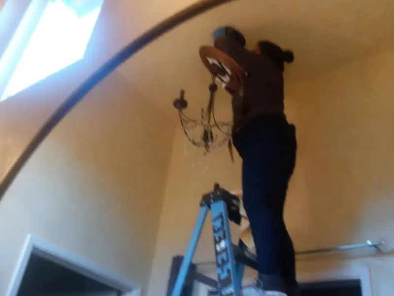 Electrician installing a chandelier in a Baton Rouge residence